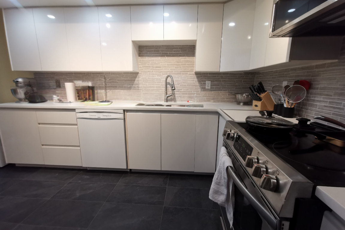 Condo Renovation in Coquitlam: Bright, modern kitchen with white cabinets, sleek countertops, and silver fittings