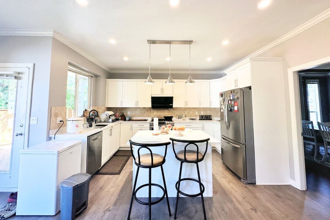 Modern kitchen at home renovation in langley, BC by Reno Stars, featuring white cabinetry, quartz countertops, and a central island with seating