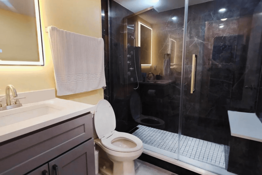 Condo Renovation in Coquitlam: Modern black and white bathroom with sleek shower, LED mirror, and practical shower seat