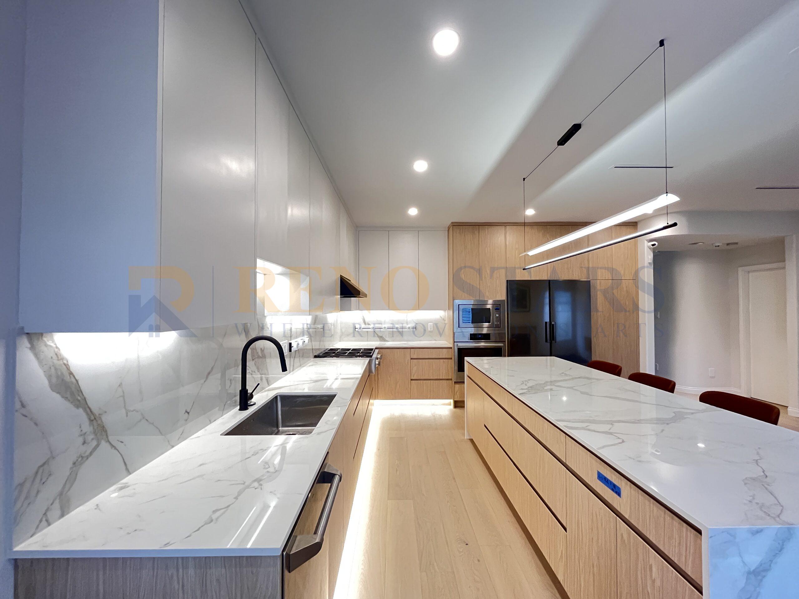 Modern kitchen renovation with marble island, sleek cabinetry, and integrated lighting.