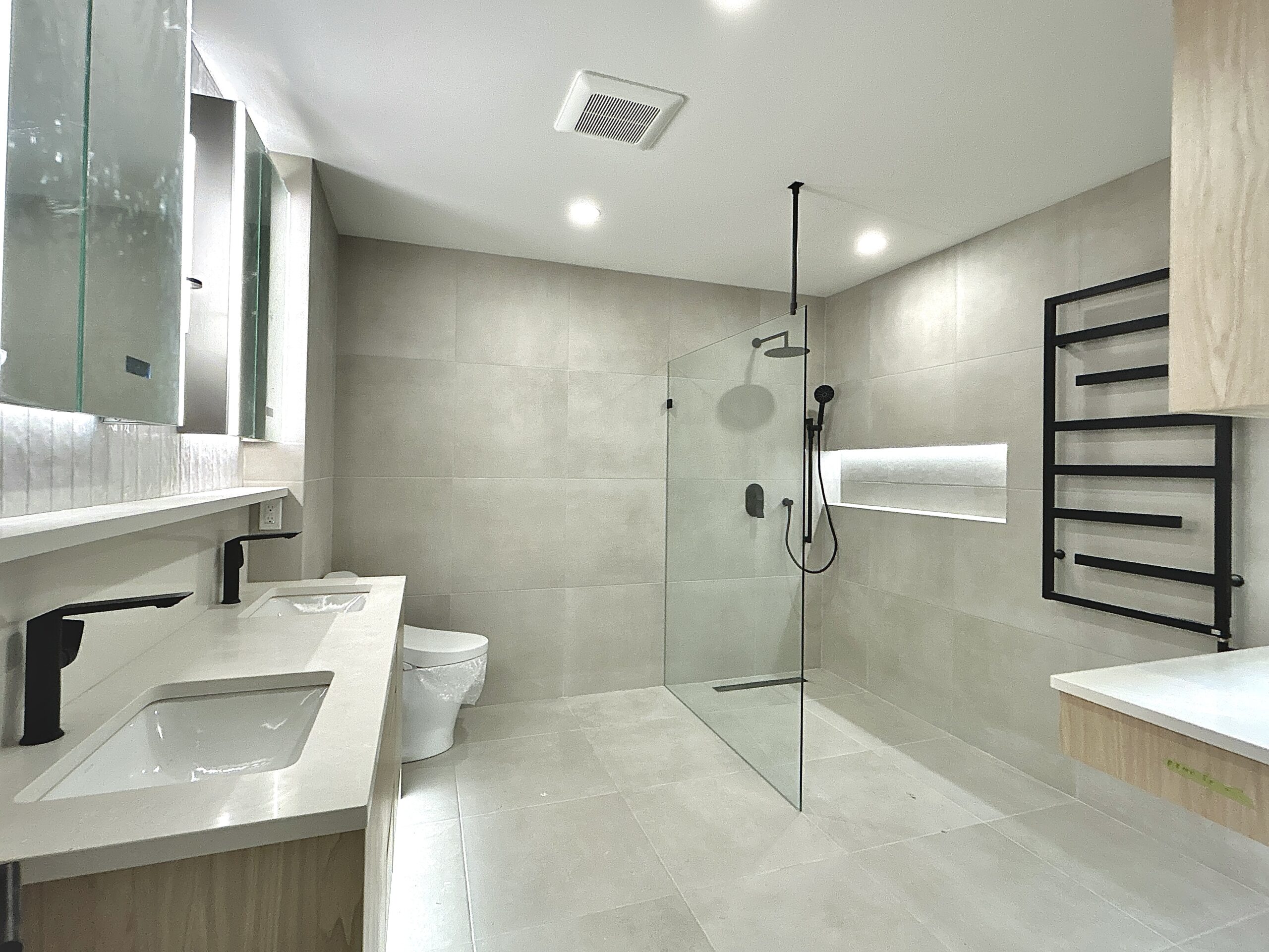Modern bathroom with double sinks, glass shower, and matte black fixtures.